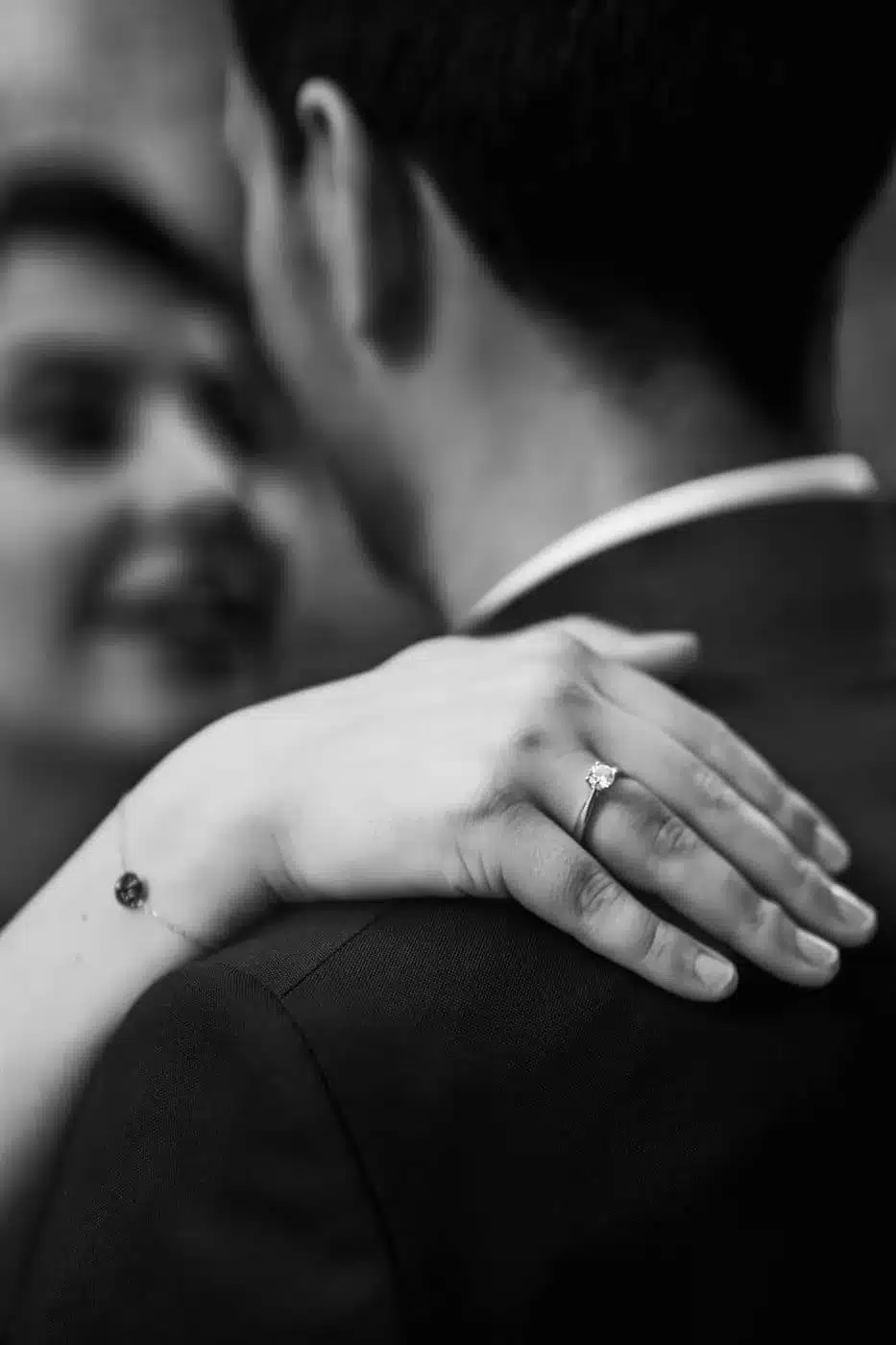 Accueil Mains de la mariée posées sur l'épaule du marié, alliance visible, en noir et blanc